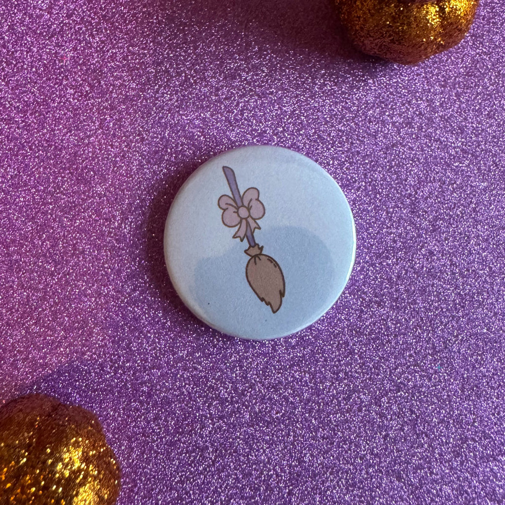 Pastel broom badge on a glittery pink background