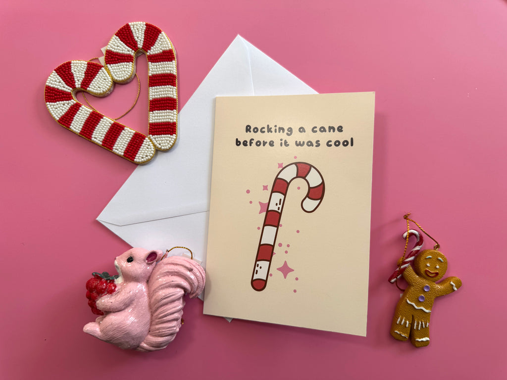 Rocking a Cane Christmas card and envelope styled on a pink background with cute festive decorations.