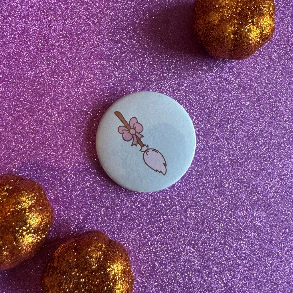 Hexecutive Dysfunction broom with bow 32mm badge on glittery pink background