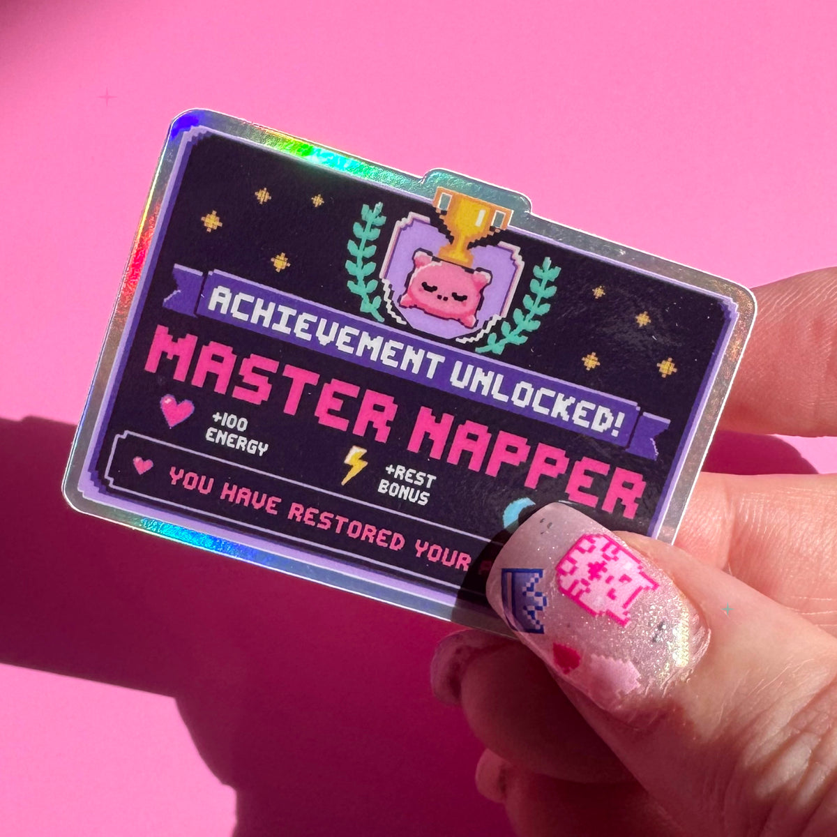 Master Napper holographic sticker held between fingers to show its size and rainbow shine