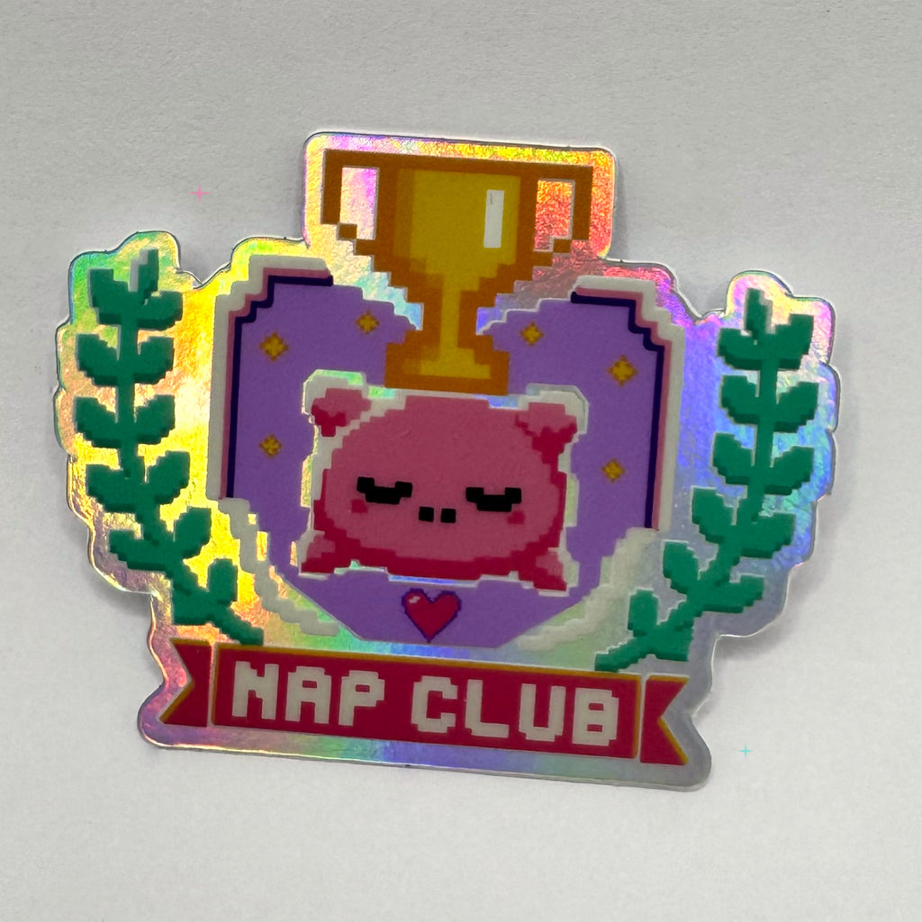 Nap Club holographic sticker featuring a sleepy pink pillow, gold trophy and leafy pixel-art design