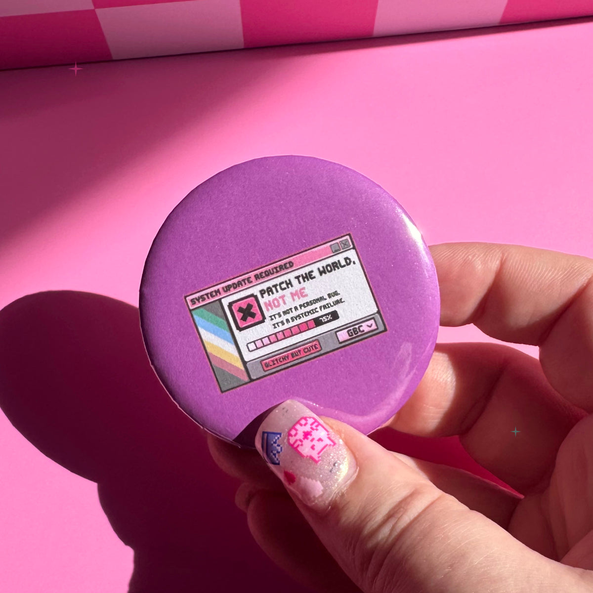 58mm purple Patch the World, Not Me button badge held between fingers for scale